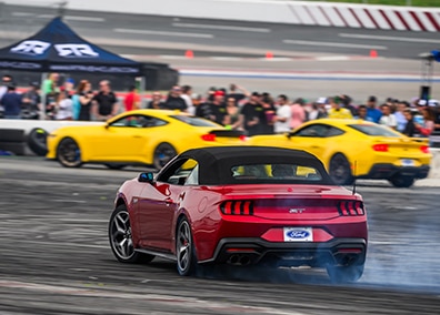 A red Ford Mustang driving at an Enthusiast event